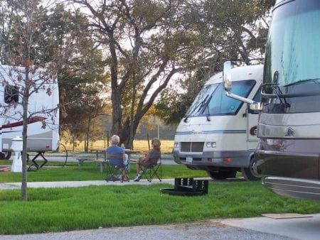 Photo of a Couple Travelers Relaxing near Their RVs. Click Here for 15 Campfire Dinner Recipes!
