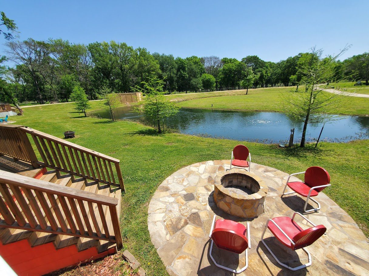 back of cottage, fire pit, chairs, pond