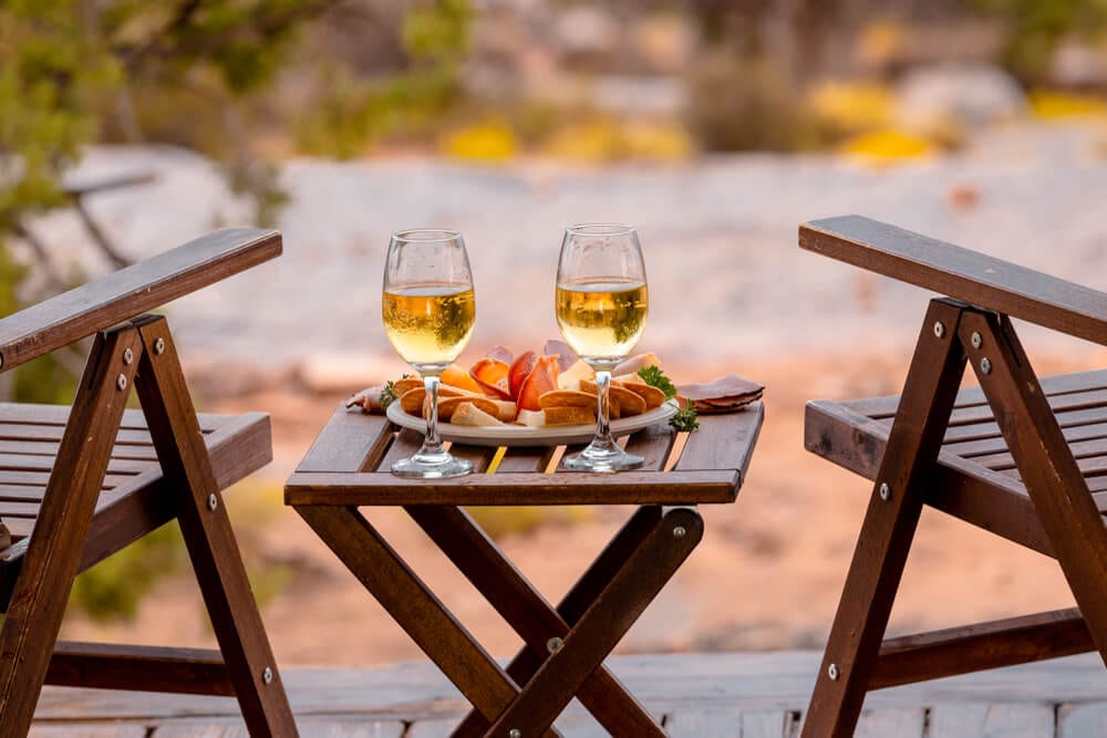 Wine glasses sit on a table between lounge chairs on the yurt deck at Mill Creek Ranch Resort.